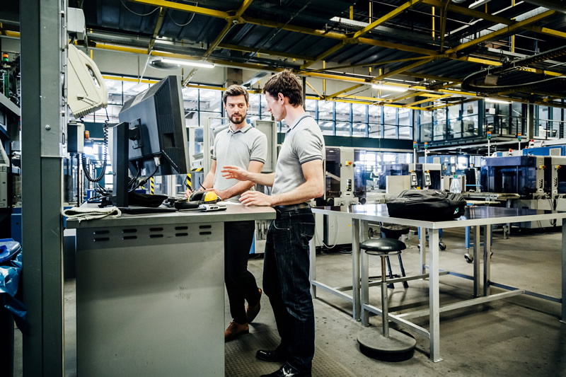 Two factory engineers working at a console together